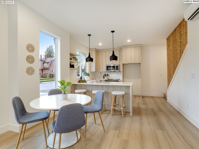 dining area featuring a wall mounted AC, sink, and light wood-type flooring