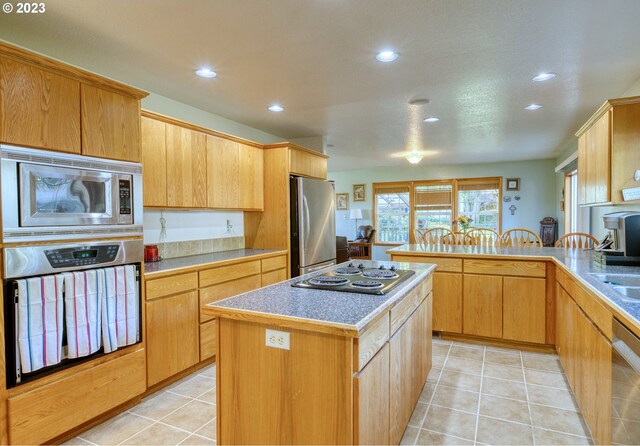 kitchen featuring light tile floors, appliances with stainless steel finishes, sink, and a center island