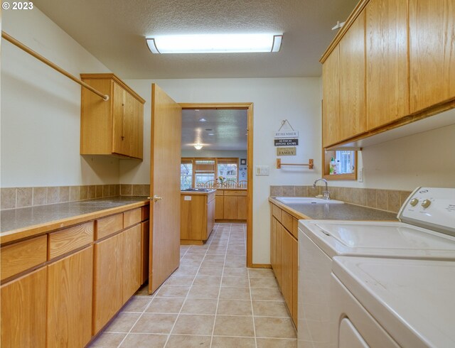 washroom with cabinets, sink, light tile floors, a textured ceiling, and separate washer and dryer