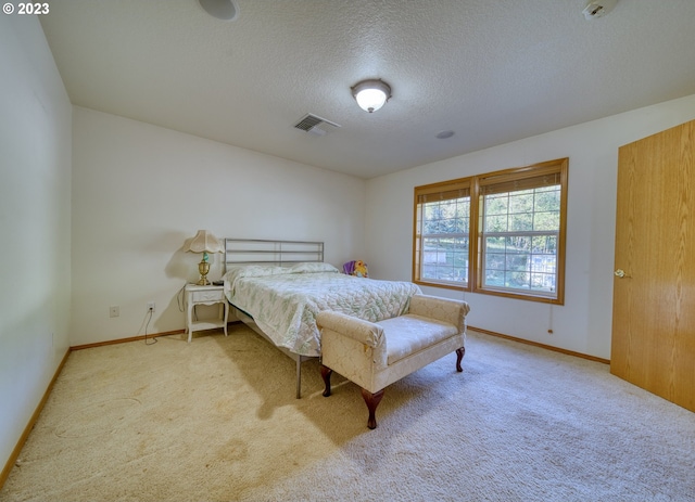 bedroom with a textured ceiling and light colored carpet