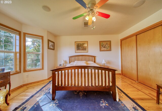 bedroom featuring ceiling fan, a closet, and light wood-type flooring