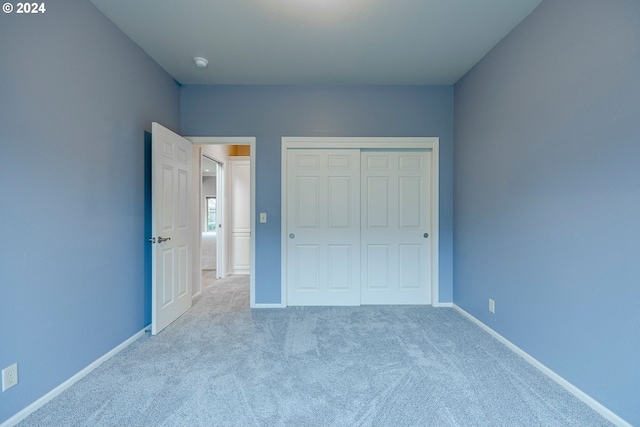 unfurnished bedroom featuring light colored carpet and a closet