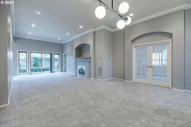 unfurnished living room with a fireplace, light carpet, french doors, and ornamental molding