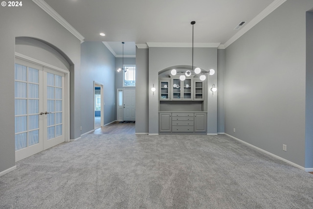 interior space with light carpet, french doors, crown molding, and a notable chandelier