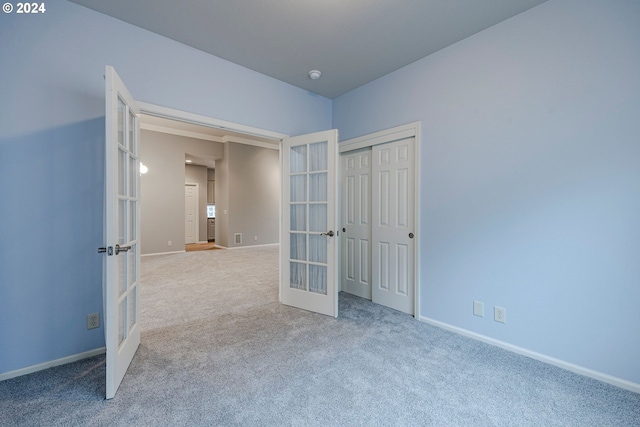 unfurnished bedroom with a closet, french doors, and carpet