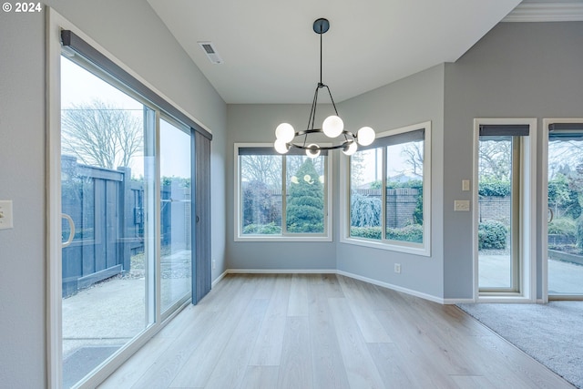 unfurnished dining area with a notable chandelier and light hardwood / wood-style flooring