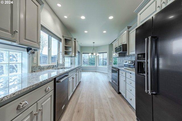 kitchen featuring appliances with stainless steel finishes, light wood-type flooring, gray cabinetry, sink, and decorative light fixtures