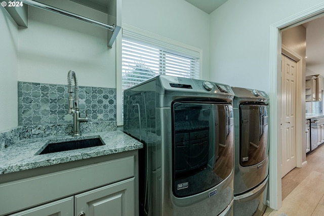 washroom featuring light hardwood / wood-style floors, washing machine and dryer, and sink