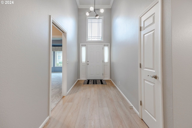 foyer entrance with an inviting chandelier, light hardwood / wood-style floors, and ornamental molding