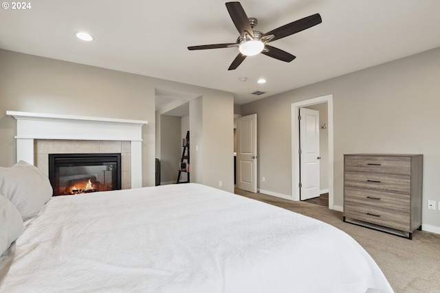 bedroom featuring ceiling fan, carpet floors, and a tiled fireplace