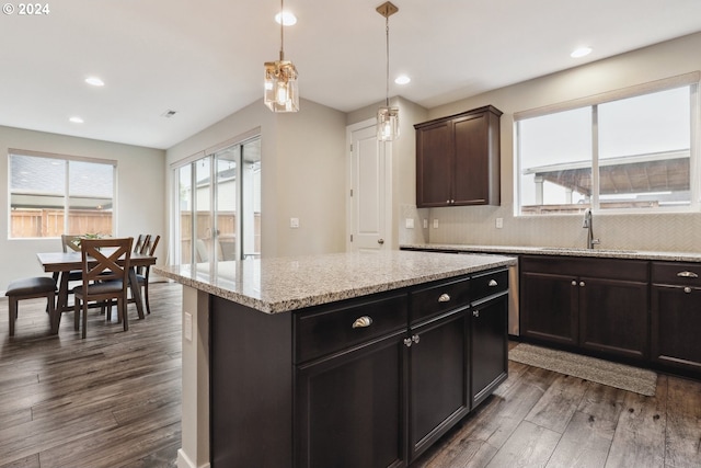 kitchen featuring hanging light fixtures, dark hardwood / wood-style floors, decorative backsplash, a kitchen island, and dark brown cabinetry