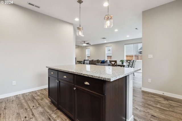 kitchen featuring pendant lighting, hardwood / wood-style flooring, ceiling fan, dark brown cabinets, and a kitchen island