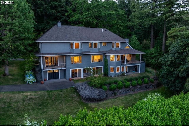 rear view of house with a lawn and a balcony