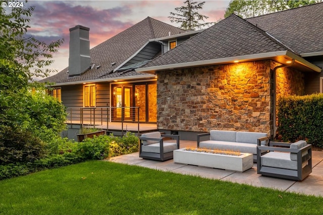 back house at dusk with a patio and an outdoor living space with a fire pit