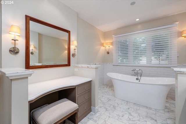 bathroom with a bathing tub, vanity, and tile walls