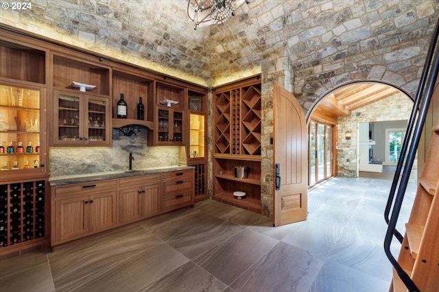 wine cellar featuring indoor wet bar, lofted ceiling, and brick ceiling