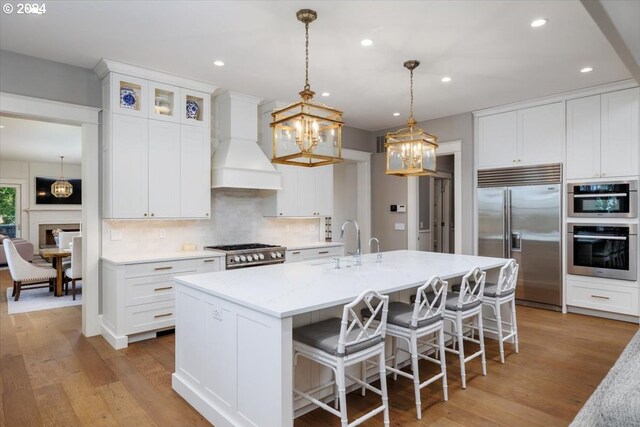 kitchen featuring sink, decorative light fixtures, dishwasher, lofted ceiling, and an island with sink