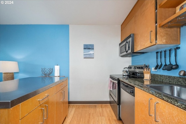 255 SW Harrison St Unit 21C, Portland, OR 97201 - kitchen featuring appliances with stainless steel finishes, light wood-style floors, a sink, and brown cabinets