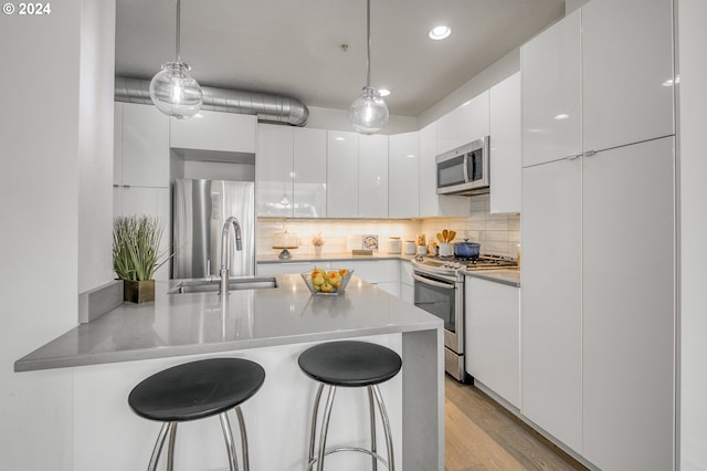 kitchen with hanging light fixtures, white cabinetry, kitchen peninsula, and appliances with stainless steel finishes