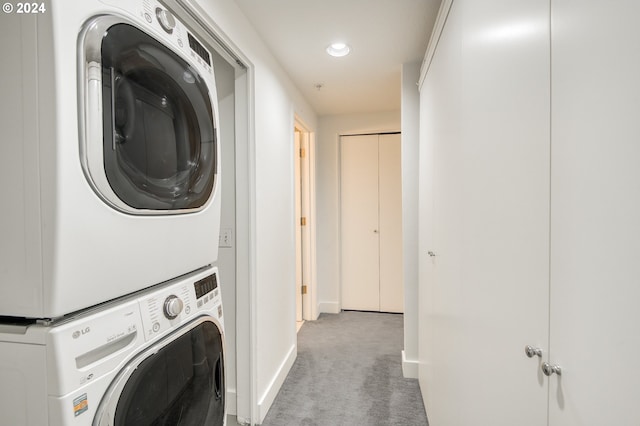 laundry room featuring stacked washer and clothes dryer and light colored carpet