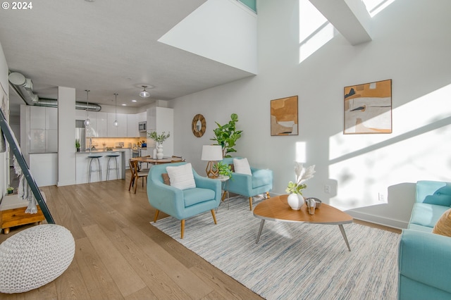 living room with light hardwood / wood-style floors and a high ceiling