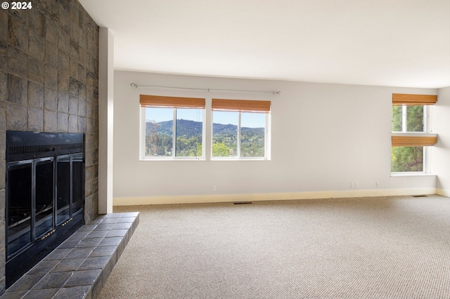 unfurnished living room featuring dark colored carpet, a tile fireplace, and a mountain view