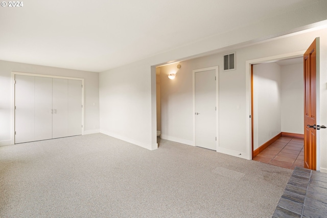 unfurnished bedroom featuring light colored carpet and a closet