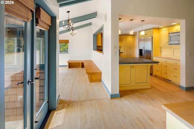 kitchen with appliances with stainless steel finishes, an inviting chandelier, a kitchen breakfast bar, light hardwood / wood-style floors, and decorative light fixtures