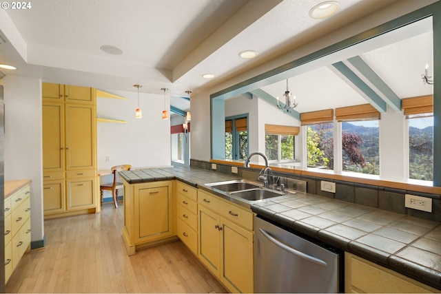 kitchen featuring sink, tile countertops, light wood-type flooring, stainless steel dishwasher, and kitchen peninsula