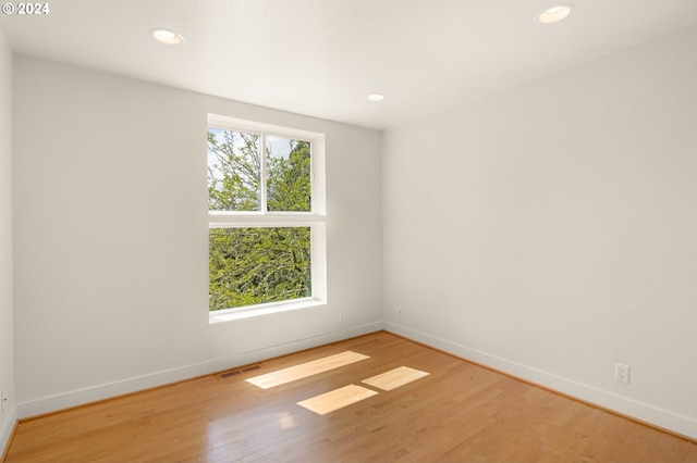 spare room with hardwood / wood-style floors and plenty of natural light