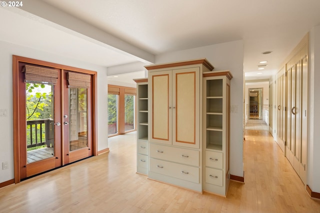 corridor with plenty of natural light, french doors, and light wood-type flooring