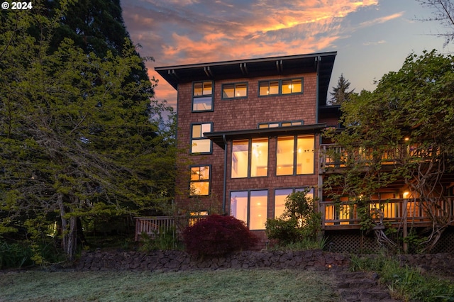 back house at dusk with a yard and a deck