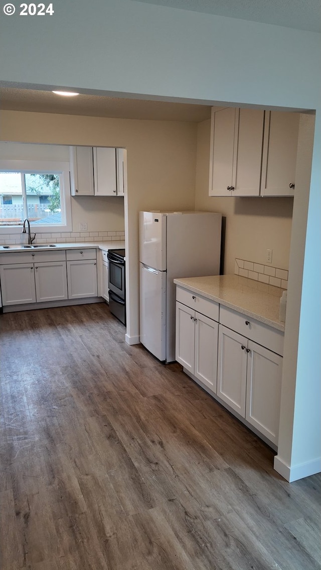 kitchen with black range with electric stovetop, white cabinets, dark hardwood / wood-style flooring, white fridge, and sink