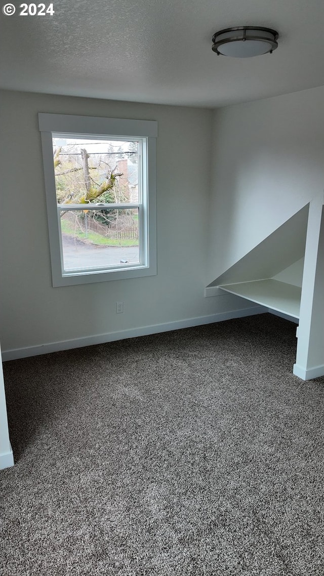 carpeted empty room featuring a textured ceiling