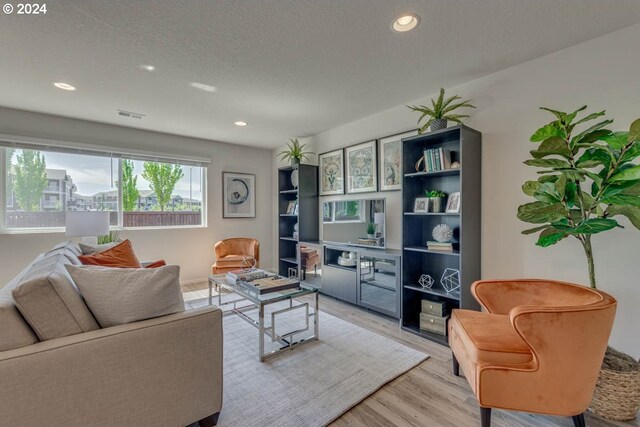 living room with a textured ceiling and light hardwood / wood-style flooring