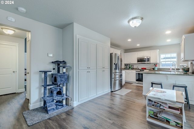 kitchen with appliances with stainless steel finishes, kitchen peninsula, white cabinets, and dark hardwood / wood-style flooring