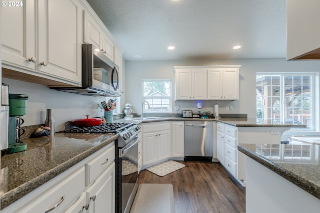 kitchen featuring appliances with stainless steel finishes, white cabinets, dark stone counters, and dark hardwood / wood-style flooring