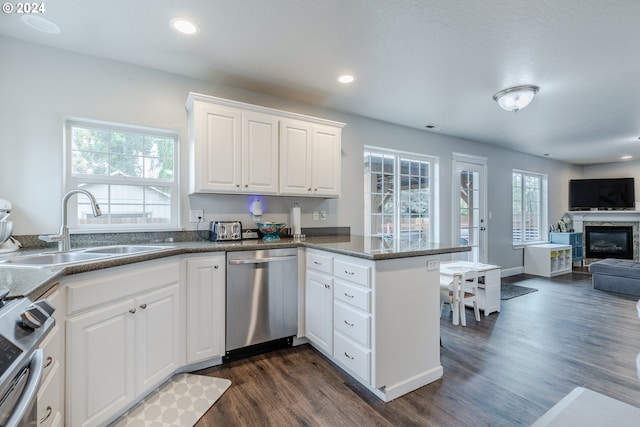 kitchen with dark wood-type flooring, kitchen peninsula, stainless steel appliances, sink, and white cabinetry