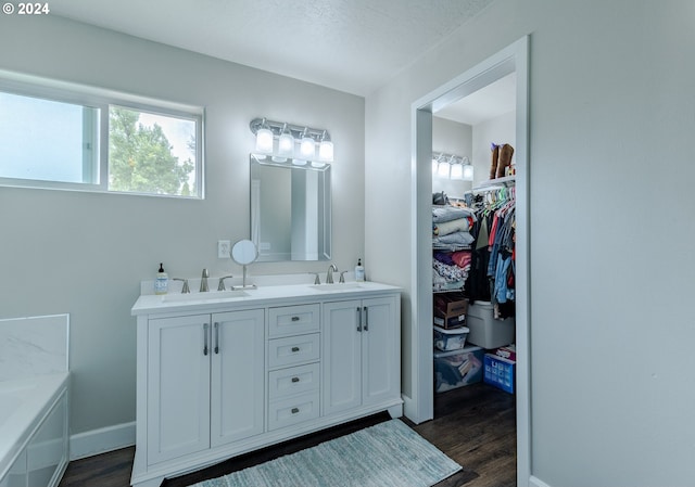 bathroom with a sink, baseboards, double vanity, and wood finished floors