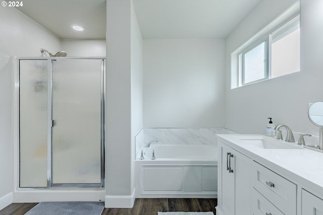 bathroom featuring vanity, baseboards, a shower stall, wood finished floors, and a garden tub