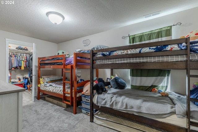 carpeted bedroom featuring a spacious closet, a textured ceiling, and a closet