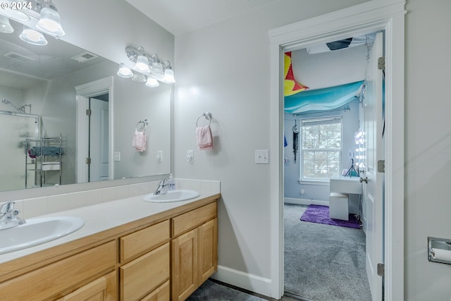 bathroom featuring double vanity, baseboards, a sink, and a stall shower