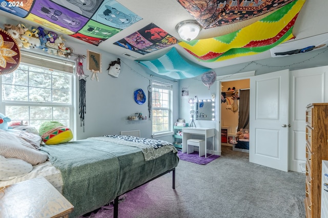 carpeted bedroom featuring multiple windows, a closet, and a walk in closet