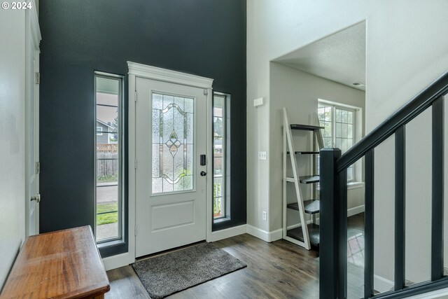 foyer featuring dark wood-style flooring, baseboards, and stairway