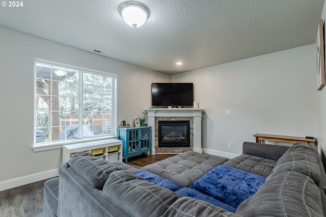living area featuring dark wood-style flooring, a premium fireplace, recessed lighting, baseboards, and visible vents