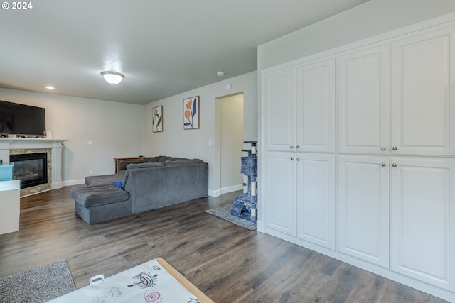 living area featuring a glass covered fireplace, baseboards, recessed lighting, and dark wood-style flooring