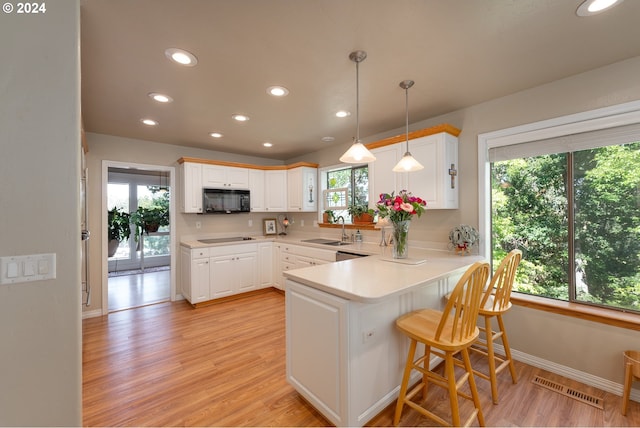 kitchen featuring black appliances, sink, a wealth of natural light, and white cabinetry