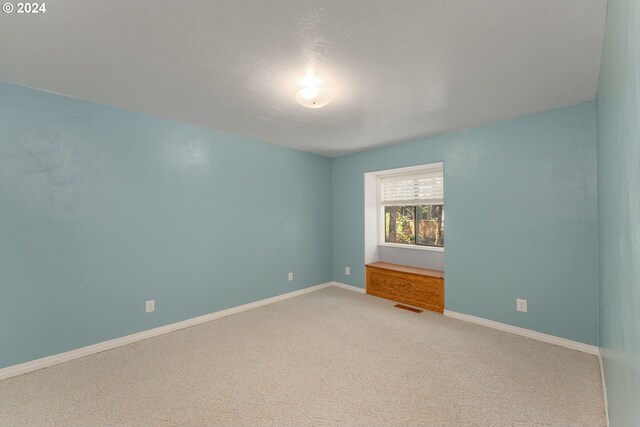 carpeted empty room featuring a textured ceiling