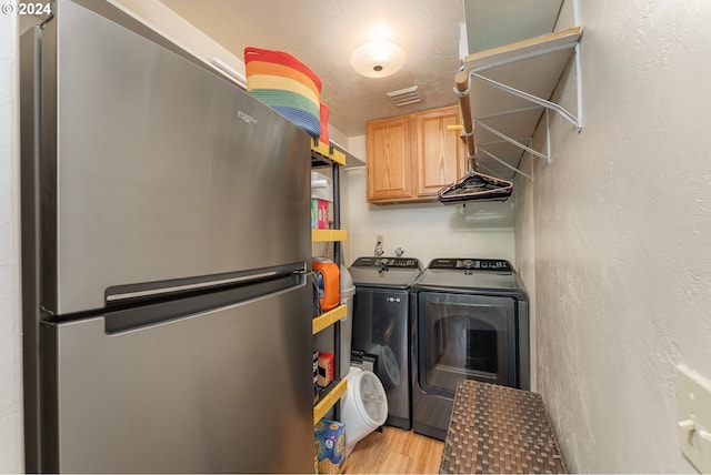 laundry area featuring separate washer and dryer, a textured ceiling, and light hardwood / wood-style flooring