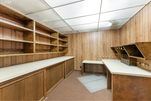 carpeted office with a paneled ceiling and wood walls